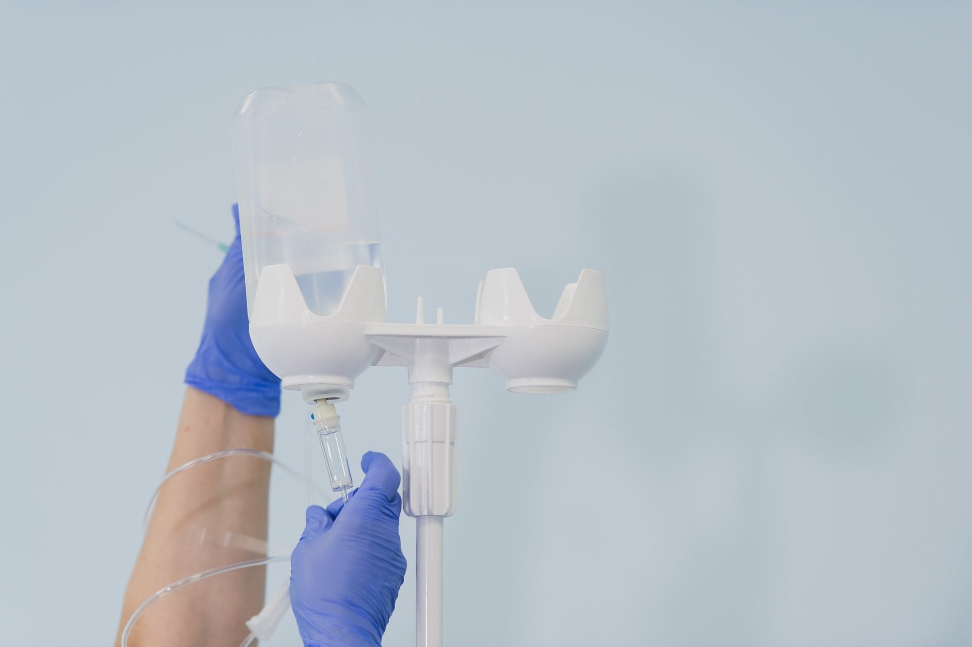Doctor's hands and infusion drip in hospital on blurred background