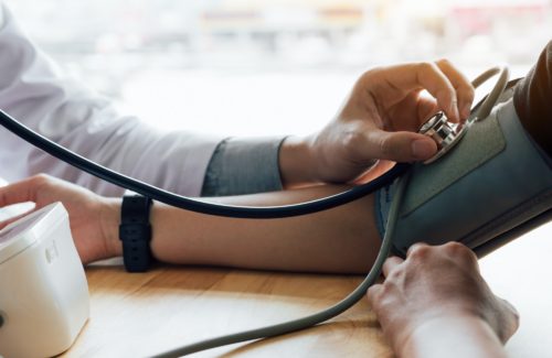 Doctor using stethoscope take a tap on the patient's arm in office room.